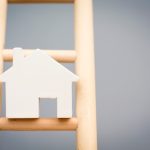 Model Houses On Rung Of Wooden Property Ladder