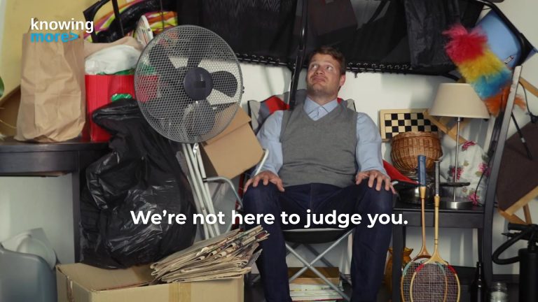 Man sitting in a very cluttered room, looking around at everything.