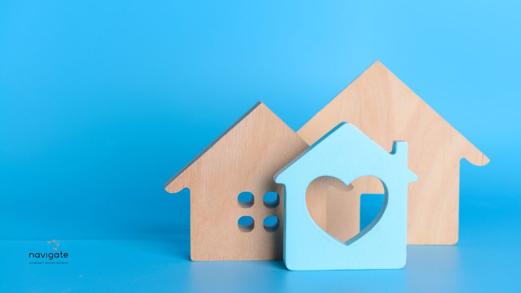 one blue house with a heart in the middle set in front of two wooden houses on blue background, apply for section 8, How to apply for a PBRA property